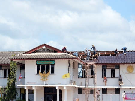 SURATTHANI, THAILAND - FEBRUARY 16 :Unidentified Thai construction workers standing on a roof of Chaiya district office covering it with tiles on February 16, 2013 in Suratthani, Thailand.のeditorial素材