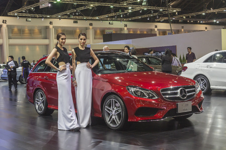 BANGKOK - APRIL 2: Unidentified lady posts at the Mercedes benz E 300 Estate car on display at The 35th Bangkok International Motor Show on April 2, 2014 in Bangkok, Thailand.のeditorial素材