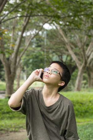 Asian Thai young boy talking on mobile phone outdoorの写真素材