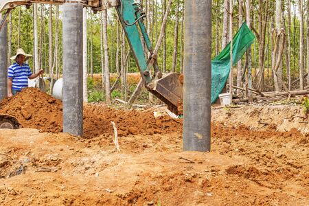 NAKHON SRI THAMMARAT THAILAND  MAY 10: Thai construction site worker watching excavator bucket digger digging on new construction site on May 10 2015 in Nakhon Sri Thammarat Thailand.のeditorial素材
