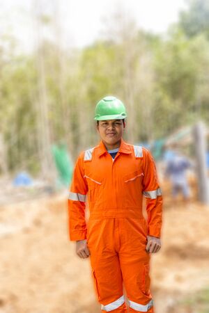 Thai construction site worker wearing high visibility safety jacket standing