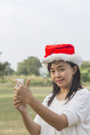 Asian Thai woman in santa hat taking picture selfie by smatrphoneの写真素材