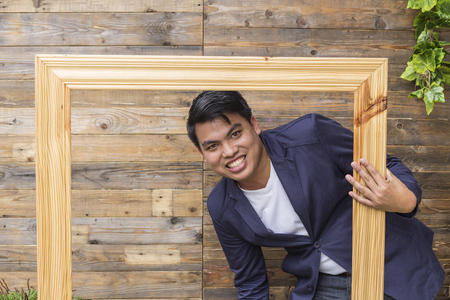 Portrait of handsome young man smiling against a wooden wallの写真素材