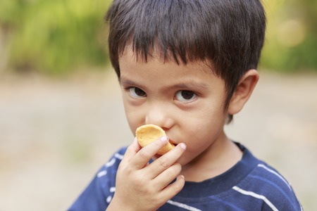 Asian little boy eating fish crispの写真素材