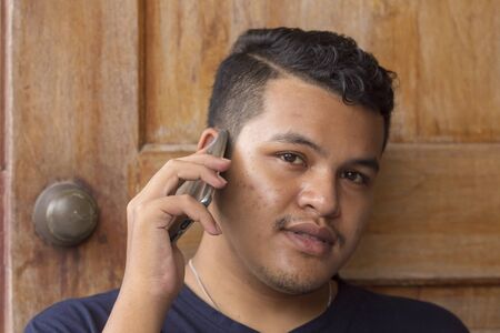 Portrait of young Asian Thai man talking on phone and looking at the camera