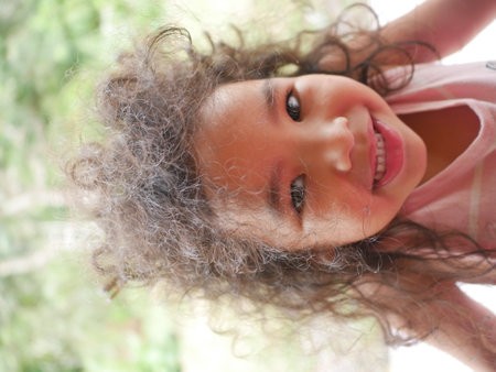 Portrait of a little girl with curly hair and a smile.の写真素材