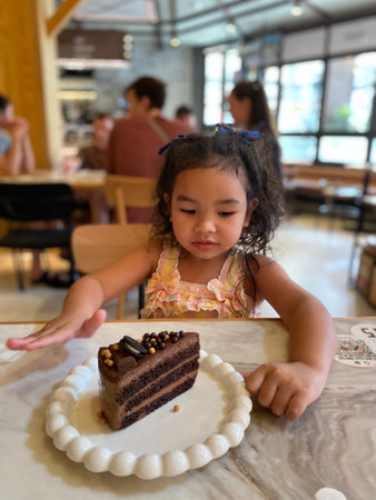 Cute little girl eating chocolate cake in a cafe. Selective focus.