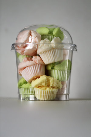 Cupcake in plastic container on white background. Selective focus.