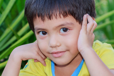 Outdoor portrait head shot of Asian little boy smiling face looking with eyes contact to cameraの写真素材