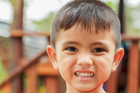Closeup cute portrait of Asian little boy smiling outdoorの写真素材