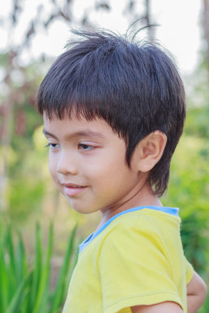 Portrait of Asian little boy against of green summer park backgroundの写真素材
