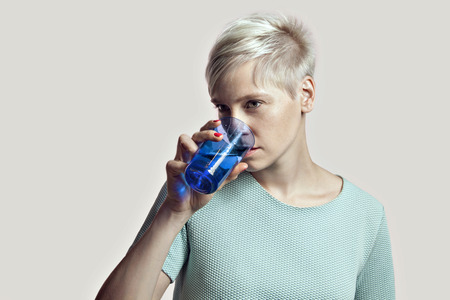 Portrait of blonde woman with glass of water, short hair, bright background