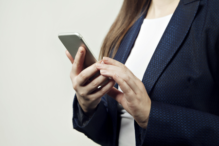 Close-up of woman hands hold phone, woman wears suitの写真素材