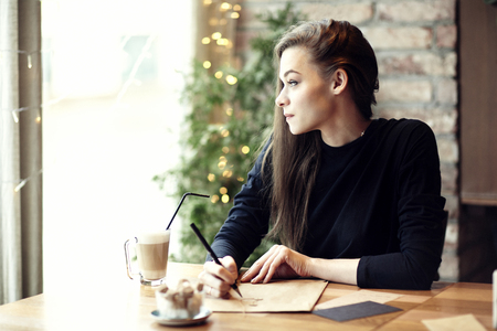 Young caucasian woman working, writing in a restaurant. Business concept. Stationary layoutsの写真素材