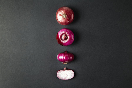 Red onion whole and sliced on black backgroundの写真素材