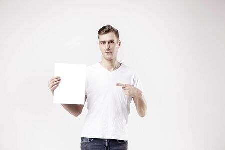 Sexy attractive man model is showing white empty space paper A4 for advertの写真素材
