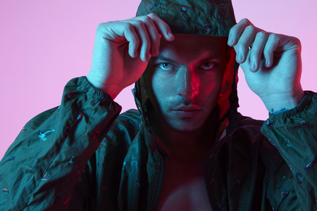 Portrait of sport fit attractive man in sportswear hoodie, color studio flash lightの写真素材