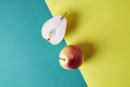 Two whole fresh pear, fruit cut in half view from above on green yellow background, modern style food picture, pattern designの写真素材