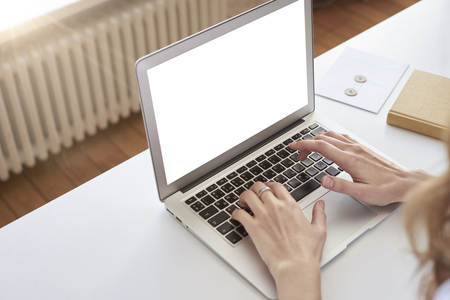 Opened laptop on woman knees, hands on keyboard, space for design layout template for mockup. Daylight in co-working.の写真素材