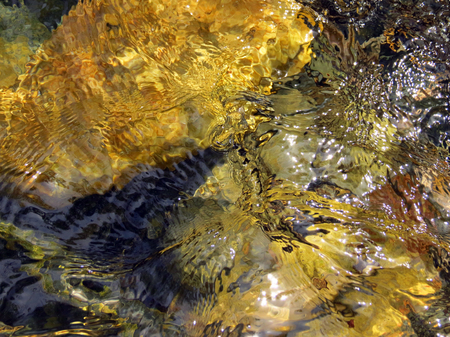 water reflection on yellow and black rocksの写真素材
