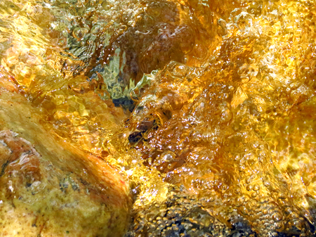 Water reflection on yellow green rocksの写真素材