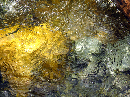 Water reflection on yellow green and blue rocksの写真素材