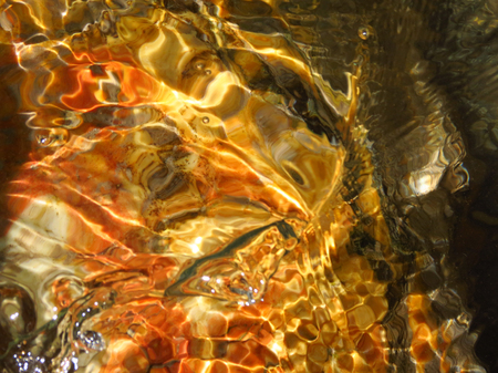 Reflection of water on orange yellow green rocksの写真素材