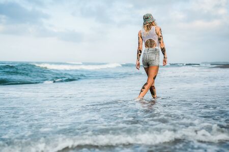 Tattooed woman walking at beachの写真素材