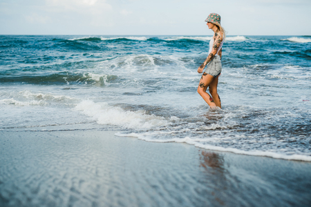 Tattooed woman walking at beachの写真素材