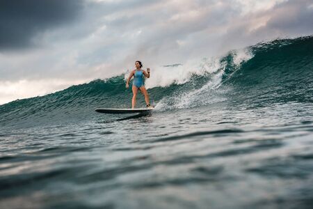 Surfer girl on Amazing Blue Wave, Bali island.