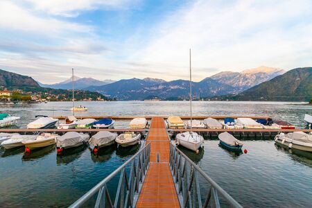 A harbor on Lake Como at sunset, with pier and boatsの写真素材