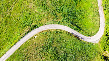 Aerial view of a road in italian countryside between fields and meadows
