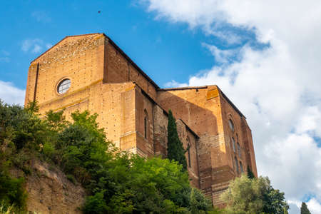 The Basilica of San Domenico, Siena, Tuscany, on a summer day with white cloudsの写真素材
