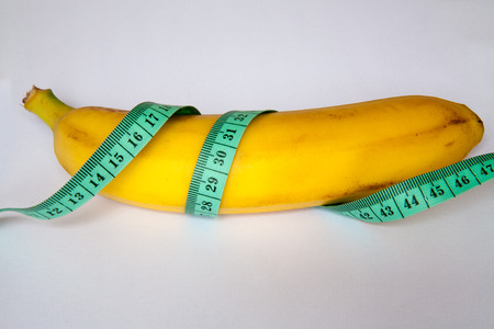 Diet concept. Banana with measuring tape closeup on white backgroundの写真素材