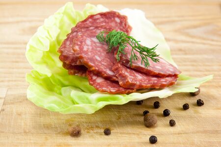 Slice of salami sausages on wooden board isolatedの写真素材