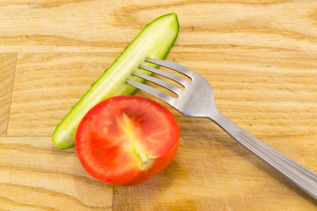 Cucumber and tomato with measuring tape over desk  - the concept of dieting and healthの写真素材