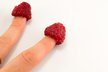 healthy eating, dieting, vegetarian food and people concept - close up of woman hands holding raspberries at homeの写真素材