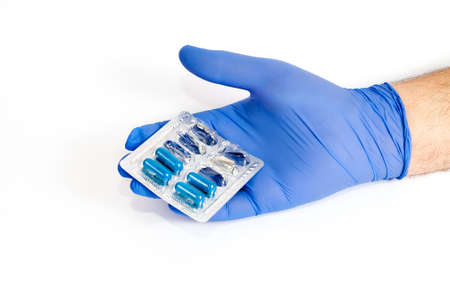 hand in a nitrile glove with blue stools on a white background