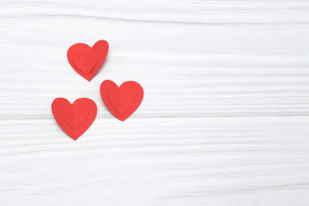 Red paper hearts hanging on white wooden background. valentines day