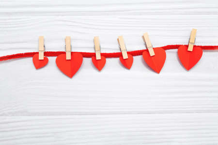 Red hearts with clothespins hanging on clothesline isolated on white wooden background. valentines dayの写真素材