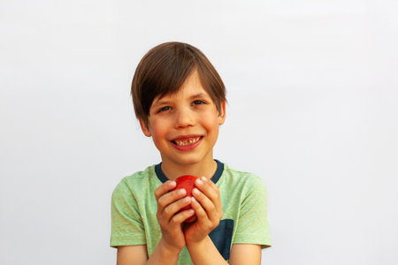 Boy 6 years old with big tasty red apple smiling on white background. Healthy food. Vitamins. Seasonal fruitsの写真素材
