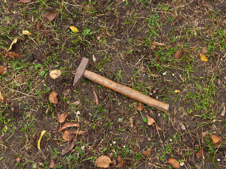 one big iron brown hammer lies on the ground and green grass in the streetの写真素材