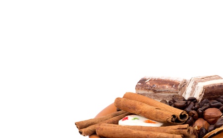 Sweets, cinnamon, nuts and coffee beans on a saucer isolated on whiteの写真素材