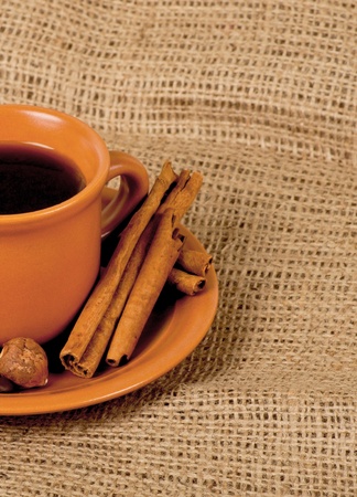 Closeup shot of freshly prepared cup of italian espresso with cinnamon, coffe beans, nuts and lemon over sackingの写真素材