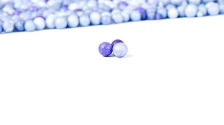 One blue and two violet little pearls isolated on background of other pearls.の写真素材