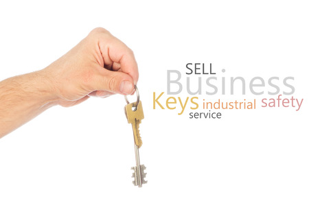 Male hand holding a car key and handing it over to another person isolatedの写真素材