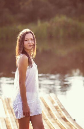 young girl sitting on the river bankの写真素材