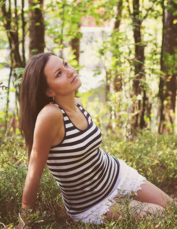 Young pensive girl in a summer forestの写真素材