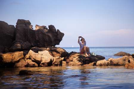 the girl makes selfie on the beach by the seaの写真素材
