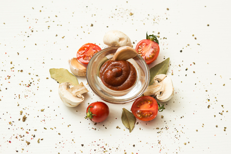 tomato paste in a glass cup and vegetables on a white backgroundの写真素材